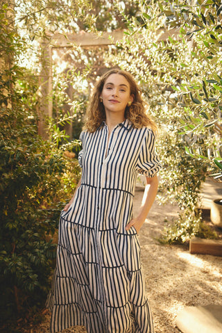 Woman in a striped dress standing in a garden with greenery around