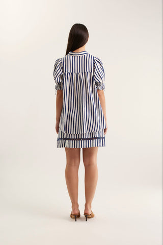 Woman wearing a navy and white striped dress on a white background